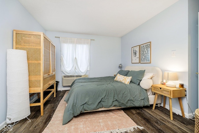 bedroom with a wall unit AC and dark hardwood / wood-style flooring