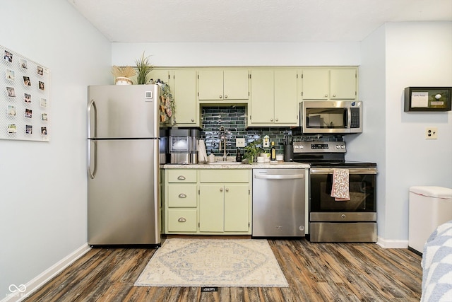 kitchen with appliances with stainless steel finishes, dark hardwood / wood-style floors, and green cabinets