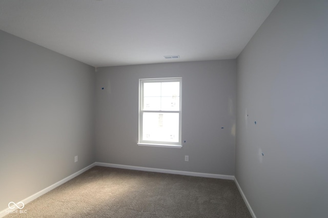 carpeted spare room with visible vents and baseboards