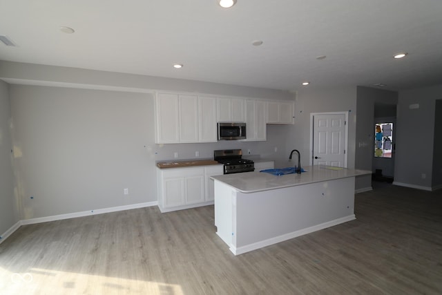 kitchen featuring white cabinets, light wood finished floors, stainless steel appliances, and a sink