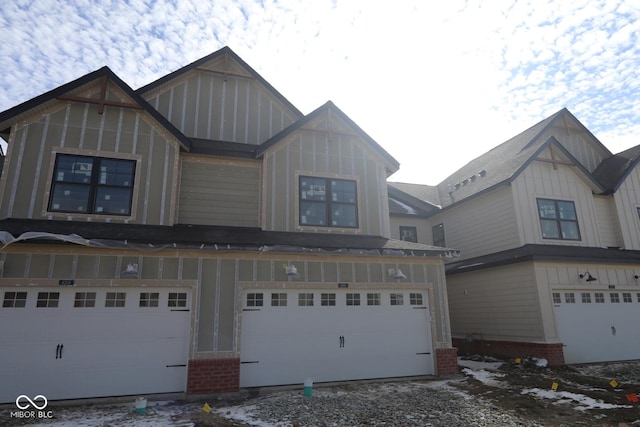 view of front of property with an attached garage, board and batten siding, and brick siding