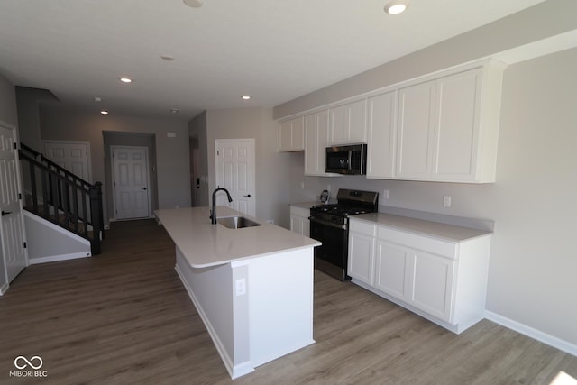 kitchen with light wood finished floors, white cabinets, stainless steel appliances, and a sink