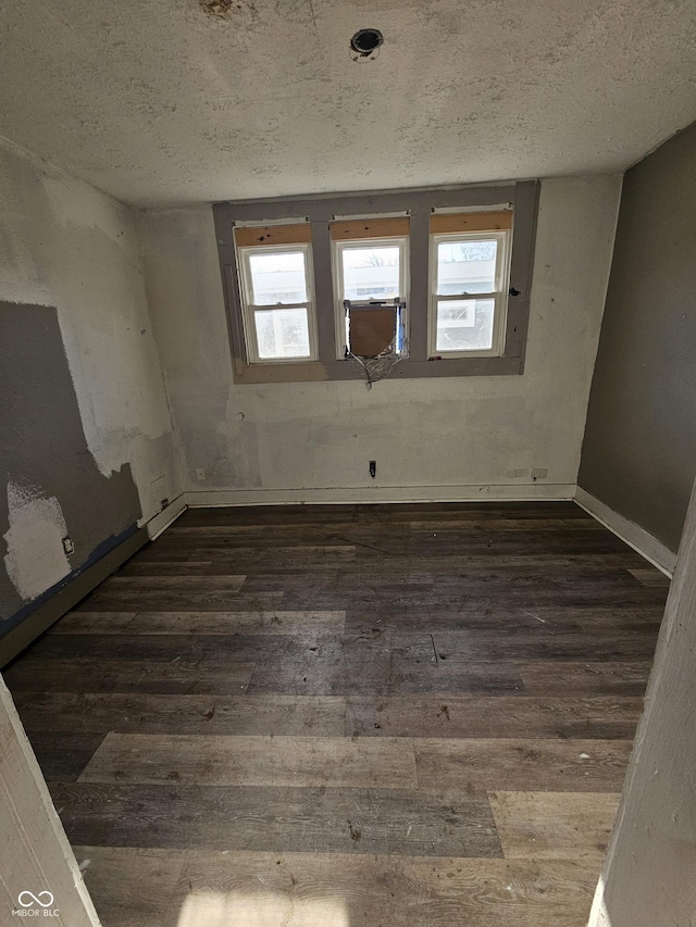 spare room featuring dark hardwood / wood-style floors, cooling unit, and a textured ceiling