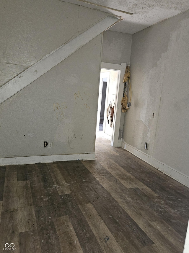 spare room with lofted ceiling and dark wood-type flooring