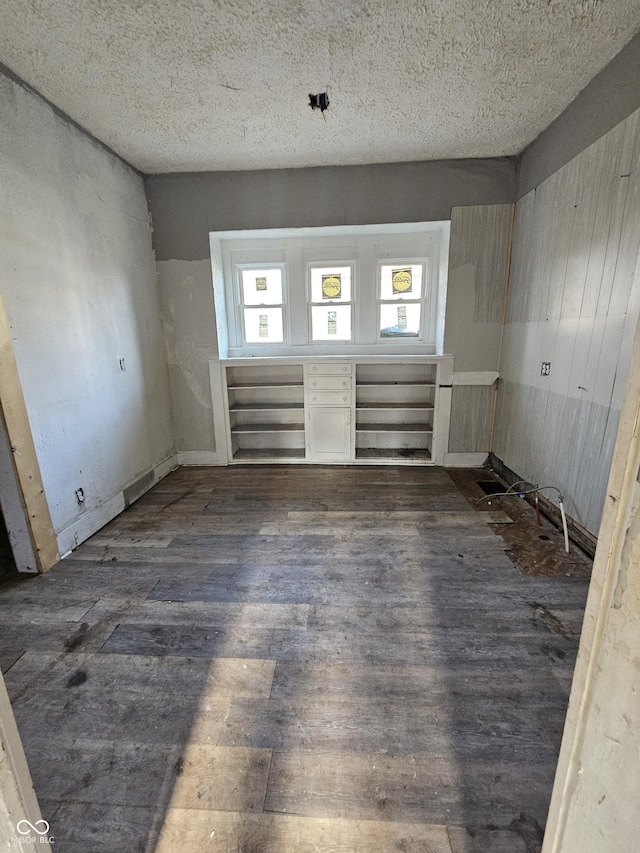 spare room with a textured ceiling, dark wood-type flooring, and a healthy amount of sunlight