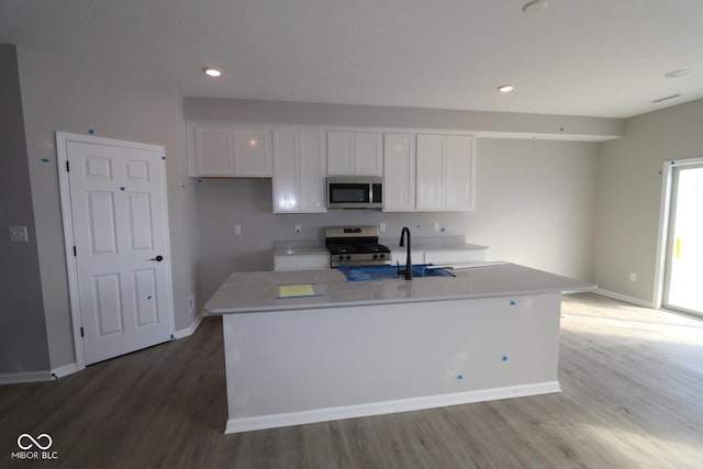 kitchen with light countertops, appliances with stainless steel finishes, white cabinets, a sink, and light wood-type flooring