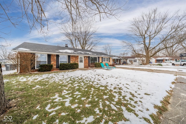 snow covered rear of property featuring a lawn