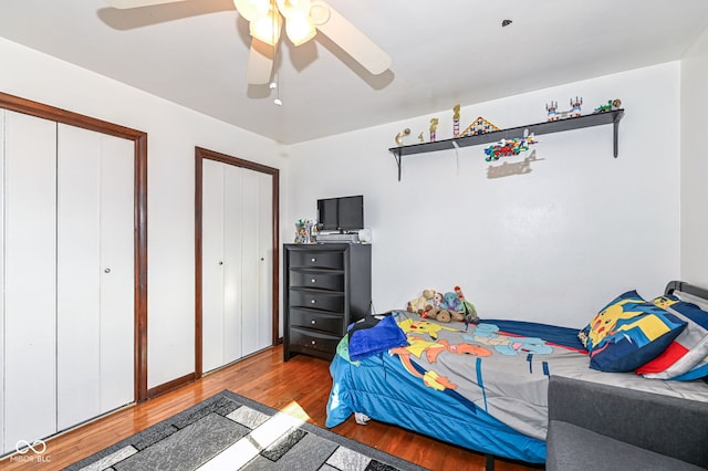 bedroom featuring multiple closets, ceiling fan, and light hardwood / wood-style flooring