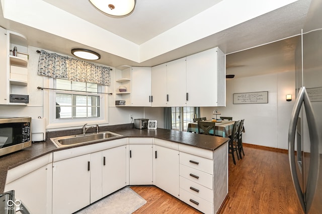 kitchen with white cabinetry, stainless steel appliances, kitchen peninsula, and sink