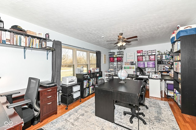 office area with ceiling fan, light hardwood / wood-style flooring, and a textured ceiling