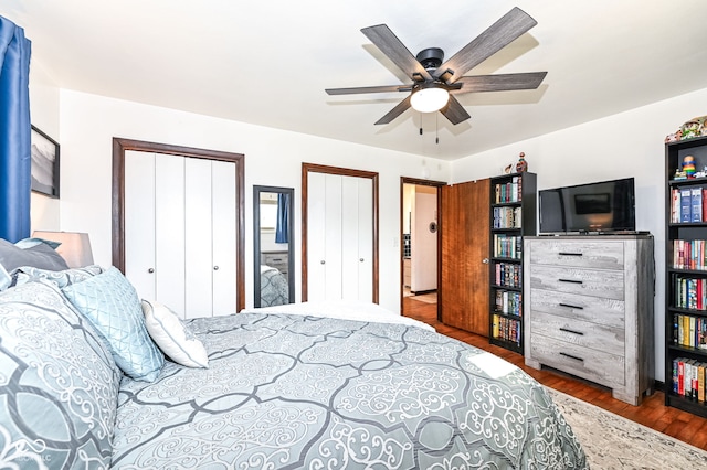 bedroom featuring hardwood / wood-style floors, multiple closets, and ceiling fan