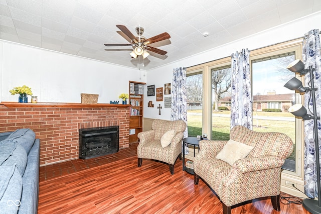 living area with a fireplace, wood-type flooring, and ceiling fan