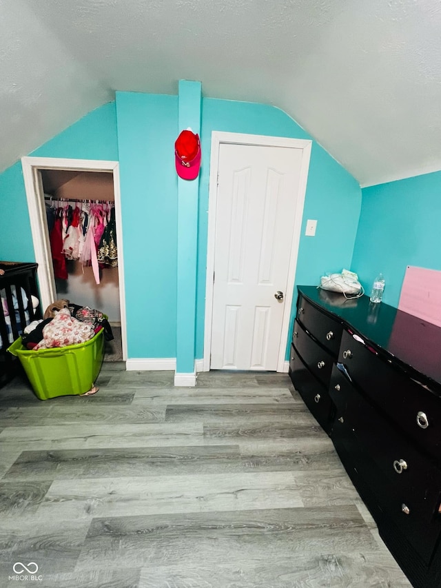 bedroom featuring lofted ceiling, hardwood / wood-style floors, and a textured ceiling