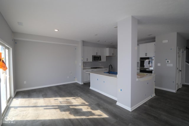 kitchen featuring appliances with stainless steel finishes, baseboards, white cabinets, and dark wood-type flooring