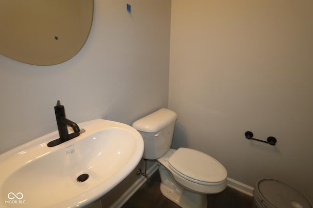 half bath featuring baseboards, a sink, and toilet