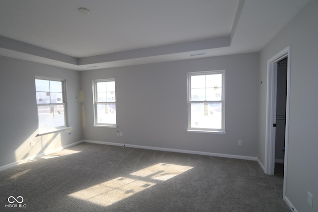 unfurnished room featuring carpet flooring, a raised ceiling, visible vents, and baseboards