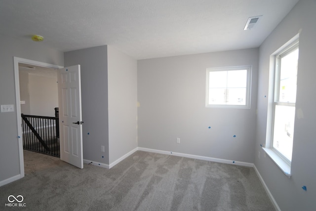 carpeted empty room featuring visible vents and baseboards