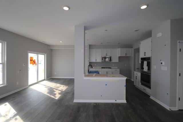 kitchen featuring white cabinetry, multiple ovens, stainless steel microwave, and a sink