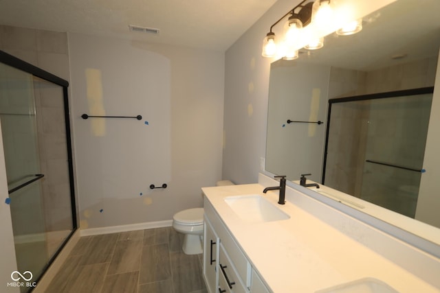 bathroom with toilet, a sink, visible vents, and a shower stall