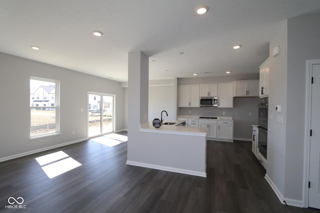 kitchen with dark wood finished floors, stainless steel microwave, white cabinets, and recessed lighting