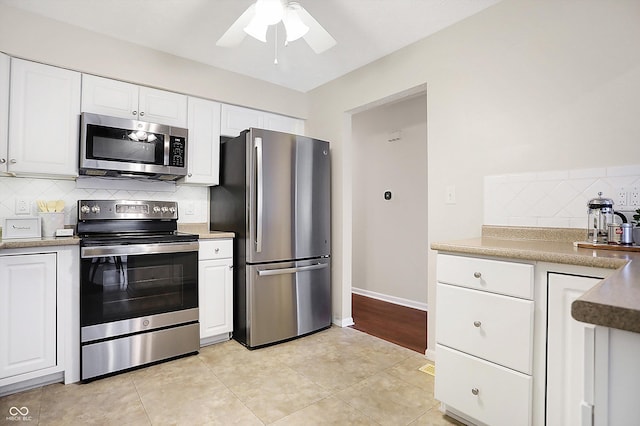 kitchen with stainless steel appliances, white cabinetry, light tile patterned floors, and backsplash