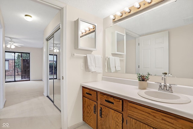 bathroom with vanity, ceiling fan, and a textured ceiling