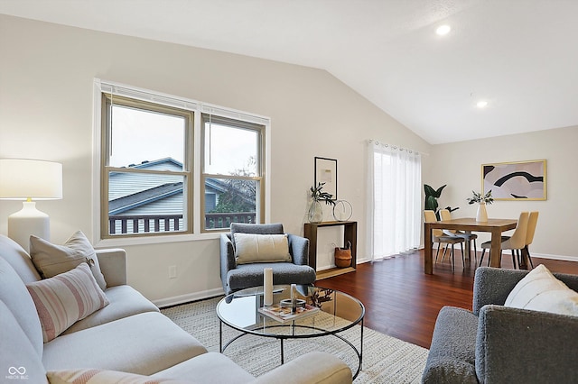 living room with lofted ceiling, a wealth of natural light, and dark hardwood / wood-style flooring