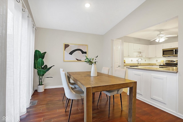 dining area with ceiling fan, vaulted ceiling, and dark hardwood / wood-style flooring