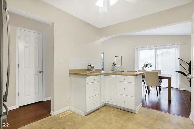 kitchen featuring lofted ceiling, white cabinets, light wood-type flooring, and kitchen peninsula