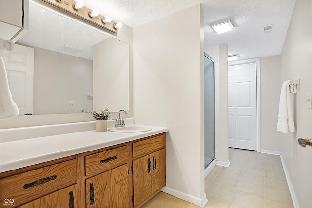 bathroom with tile patterned flooring, vanity, an enclosed shower, and a textured ceiling