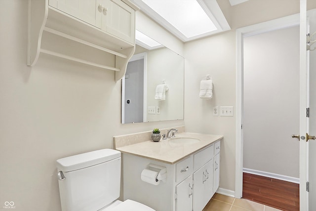 bathroom featuring vanity, a skylight, tile patterned floors, and toilet