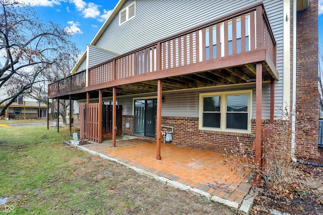 rear view of property with a wooden deck, a patio area, and a lawn