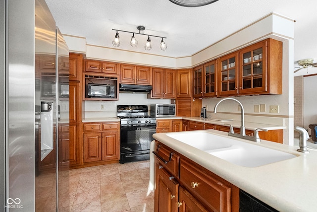 kitchen featuring glass insert cabinets, range hood, light countertops, and black appliances