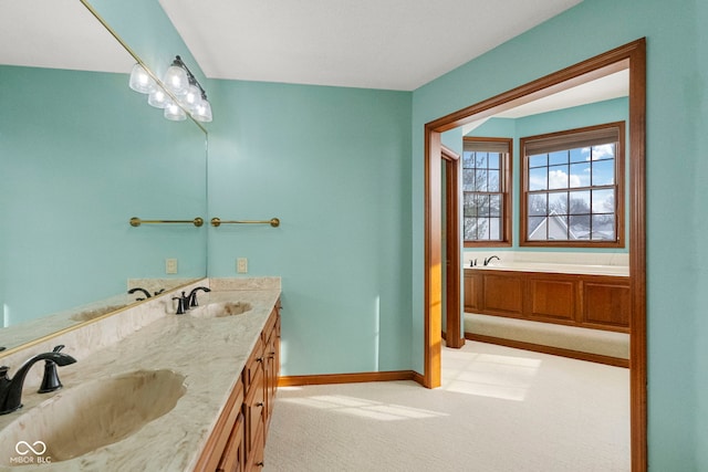 bathroom featuring double vanity, a sink, baseboards, and a bath