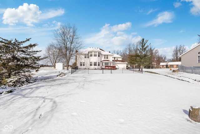 snow covered rear of property featuring fence