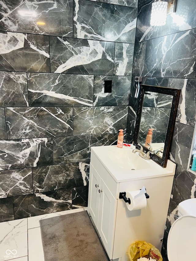 bathroom with vanity, tile walls, and toilet