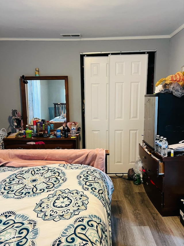 bedroom featuring crown molding, hardwood / wood-style flooring, and a closet