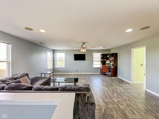 living room with hardwood / wood-style flooring, a textured ceiling, and ceiling fan