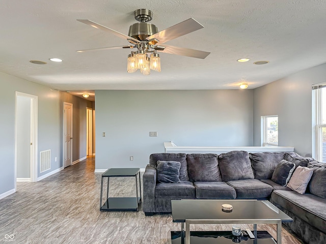 living room featuring ceiling fan and a textured ceiling