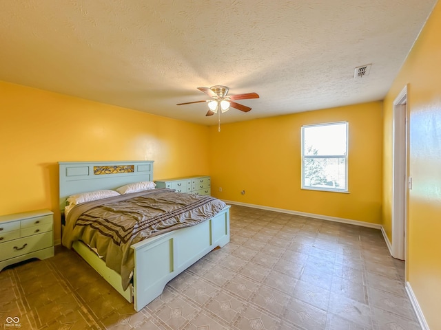 bedroom with ceiling fan and a textured ceiling