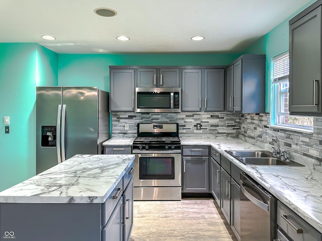 kitchen with tasteful backsplash, light stone countertops, appliances with stainless steel finishes, and sink