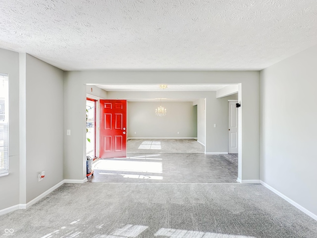 carpeted spare room featuring an inviting chandelier and a textured ceiling