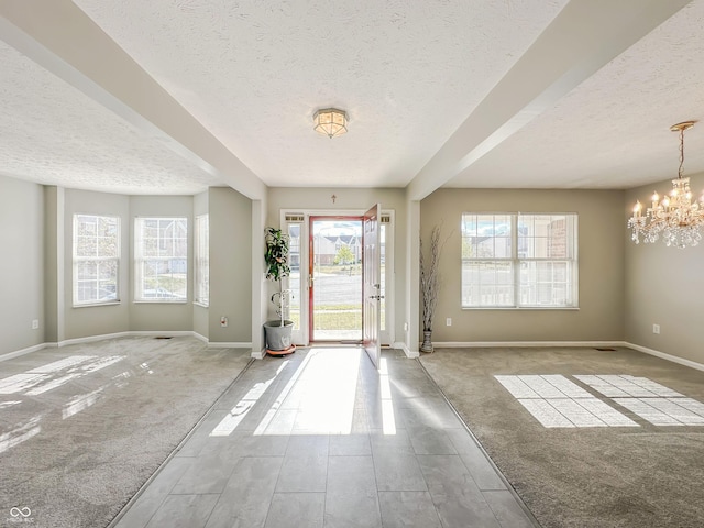 foyer entrance with a textured ceiling, light carpet, and a notable chandelier