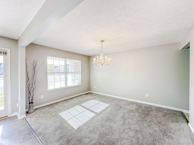 unfurnished room featuring a notable chandelier, a textured ceiling, and carpet