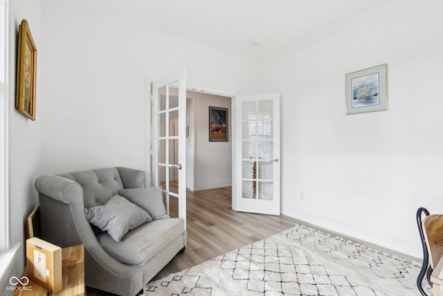 living area featuring crown molding, french doors, and light wood-type flooring