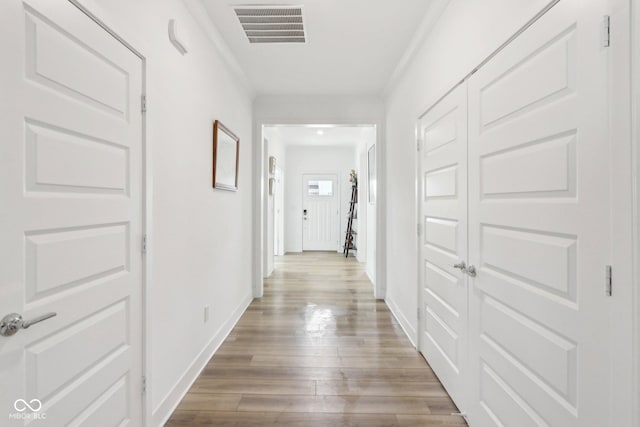 hallway featuring ornamental molding and light wood-type flooring