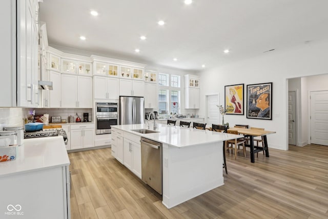 kitchen with appliances with stainless steel finishes, white cabinetry, an island with sink, sink, and a kitchen breakfast bar