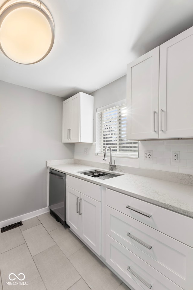 kitchen featuring white cabinetry, light tile patterned flooring, dishwashing machine, and sink