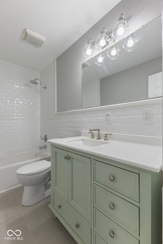 full bathroom featuring toilet, tile walls, vanity, tiled shower / bath combo, and tile patterned flooring