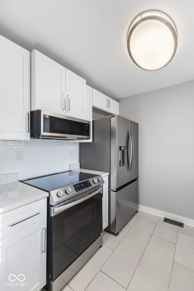 kitchen with white cabinetry, appliances with stainless steel finishes, light tile patterned floors, and backsplash